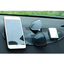Black oval silicone anti-slip dashboard mat with textured surface and center cutout on dash.