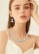Imitation pearl necklace and dangling earrings on model, silver-toned clasp