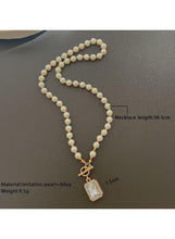 Imitation pearl necklace with gold-tone bow charm and square pendant