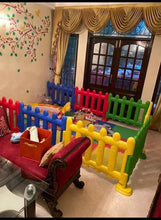 Colorful plastic play yard fence sections with rounded top rails and corner posts