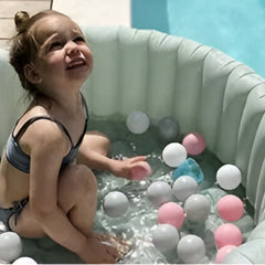 Child playing in an inflatable pool with pastel colored indoor kids play balls 50 pack by Huitich