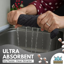 Dark gray kitchen towel being wrung above a sink