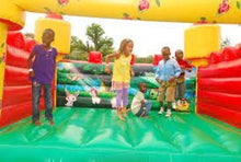 Inflatable bouncing house play area with green floor, red walls, and castle arches