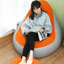 Inflatable orange lounge chair with curved gray base and built-in footrest
