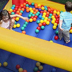 Children playing in colorful inflatable water slide for kids with multi-colored plastic balls