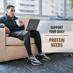 Man on couch with laptop drinking shake promoting Isopure low carb whey protein powder for daily protein