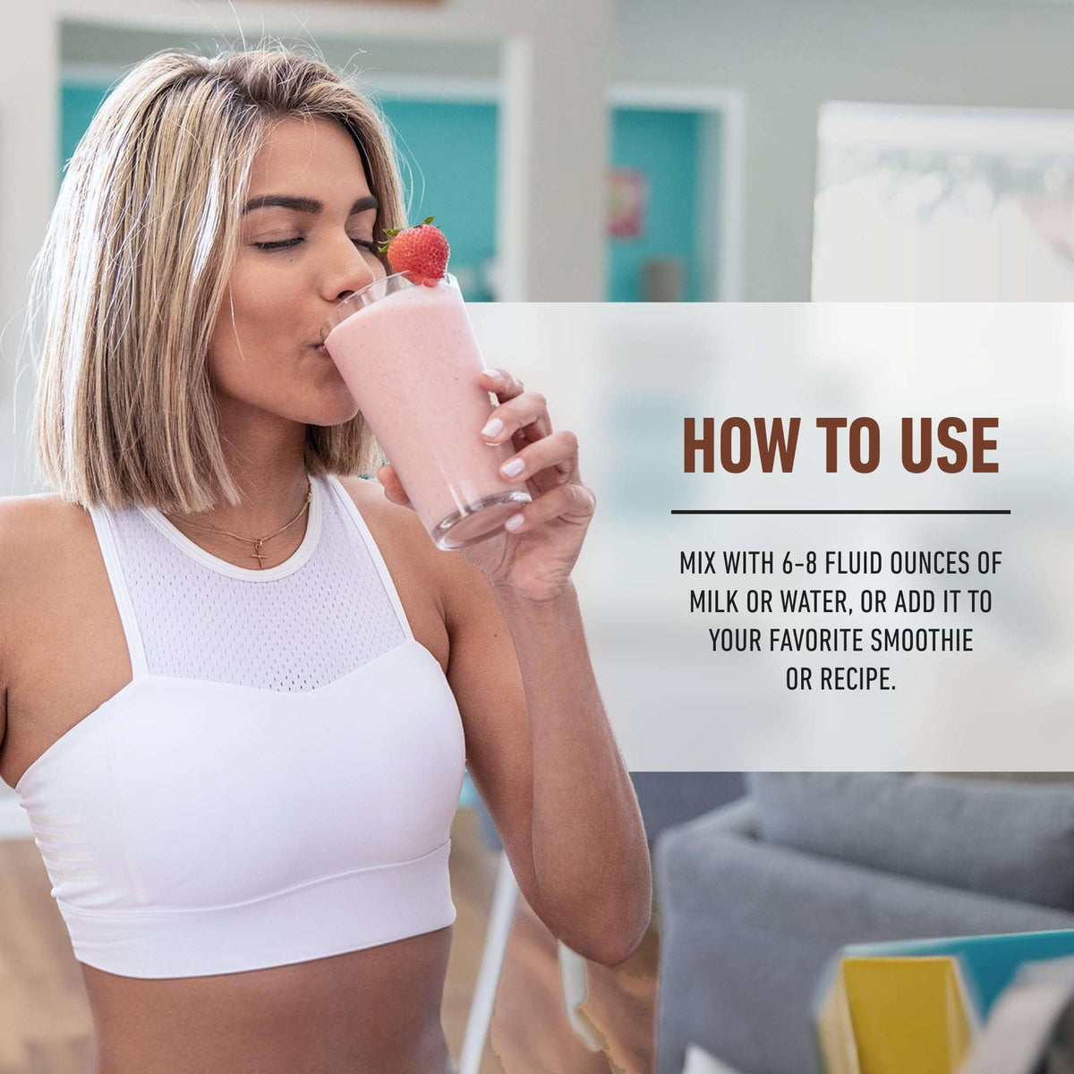 Woman in white sports bra drinking a pink strawberry smoothie using Isopure low carb whey protein powder in home