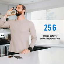 Man drinking from protein powder tub while standing at a table