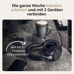 Jabra Evolve2 85 wireless headset placed on a desk next to a coffee cup and smartphone showing long battery life