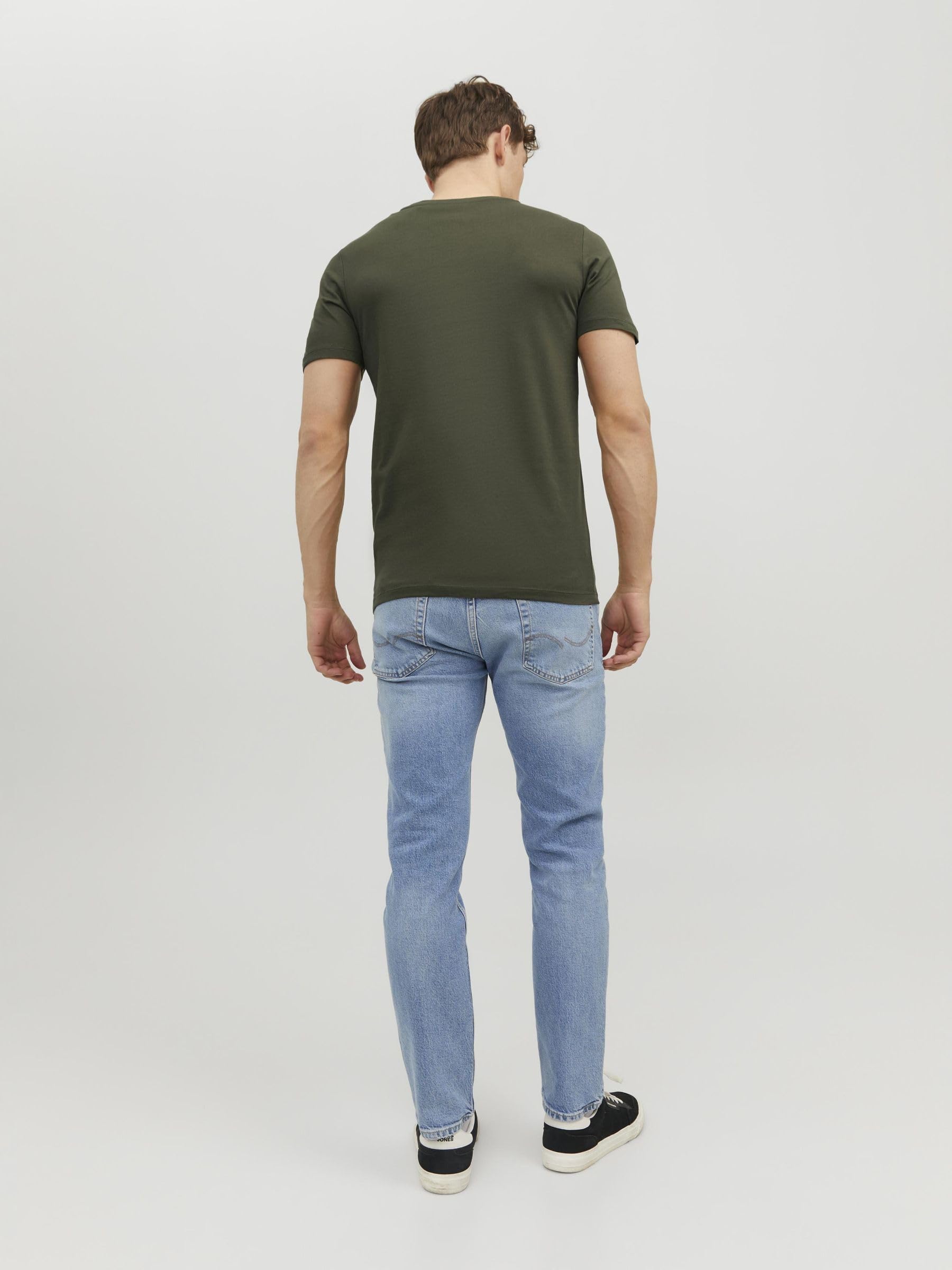 Back view of a man wearing a green crew neck t-shirt men paired with light blue jeans and black sneakers