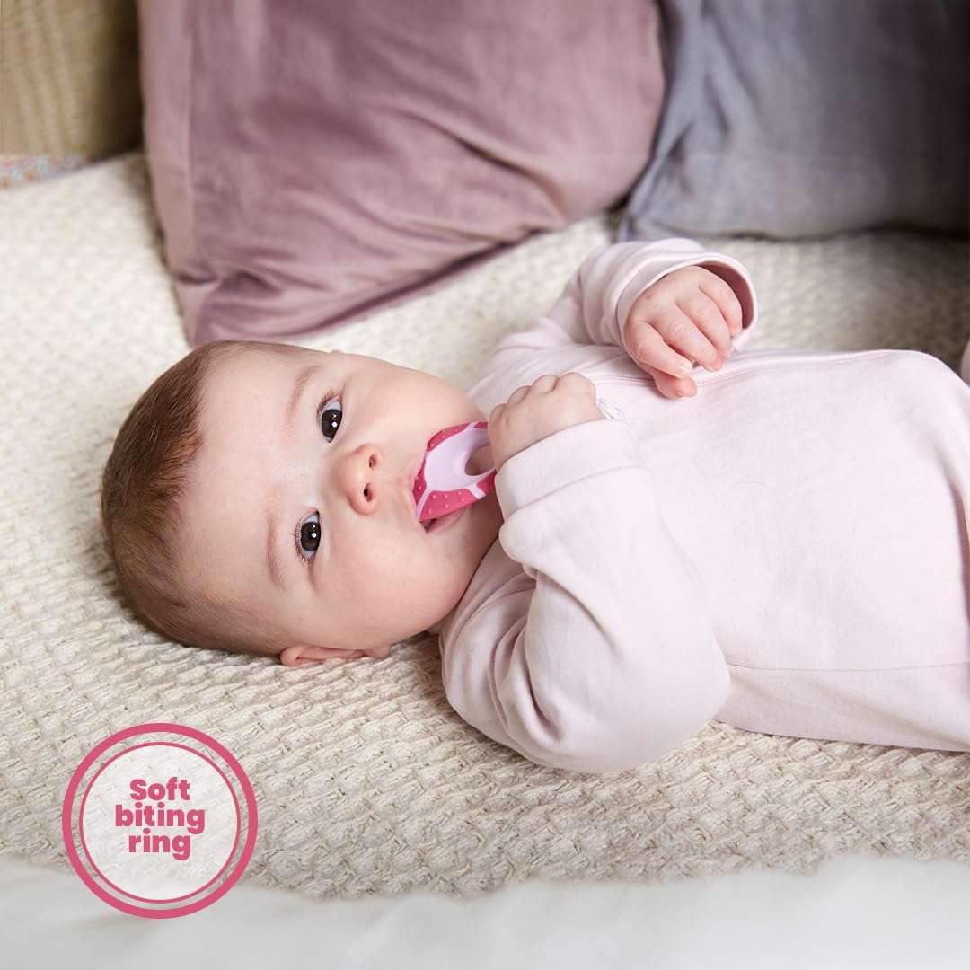 Jordan soft bristle toothbrush for infants pink teether toothbrush held by a baby lying on a blanket