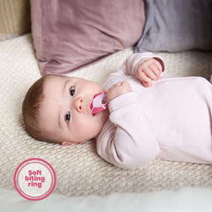 Jordan soft bristle toothbrush for infants pink teether toothbrush held by a baby lying on a blanket
