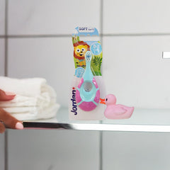 Jordan soft bristle toothbrush for infants packaged with lion design on bathroom shelf next to pink rubber duck