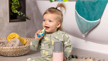 Baby holding a teal baby toothbrush with soft bristles