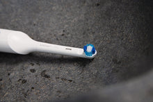 Close-up of a whitening toothbrush head with blue bristles on white handle