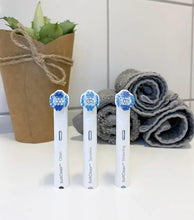 Three whitening toothbrushes with white handles and blue bristle heads standing