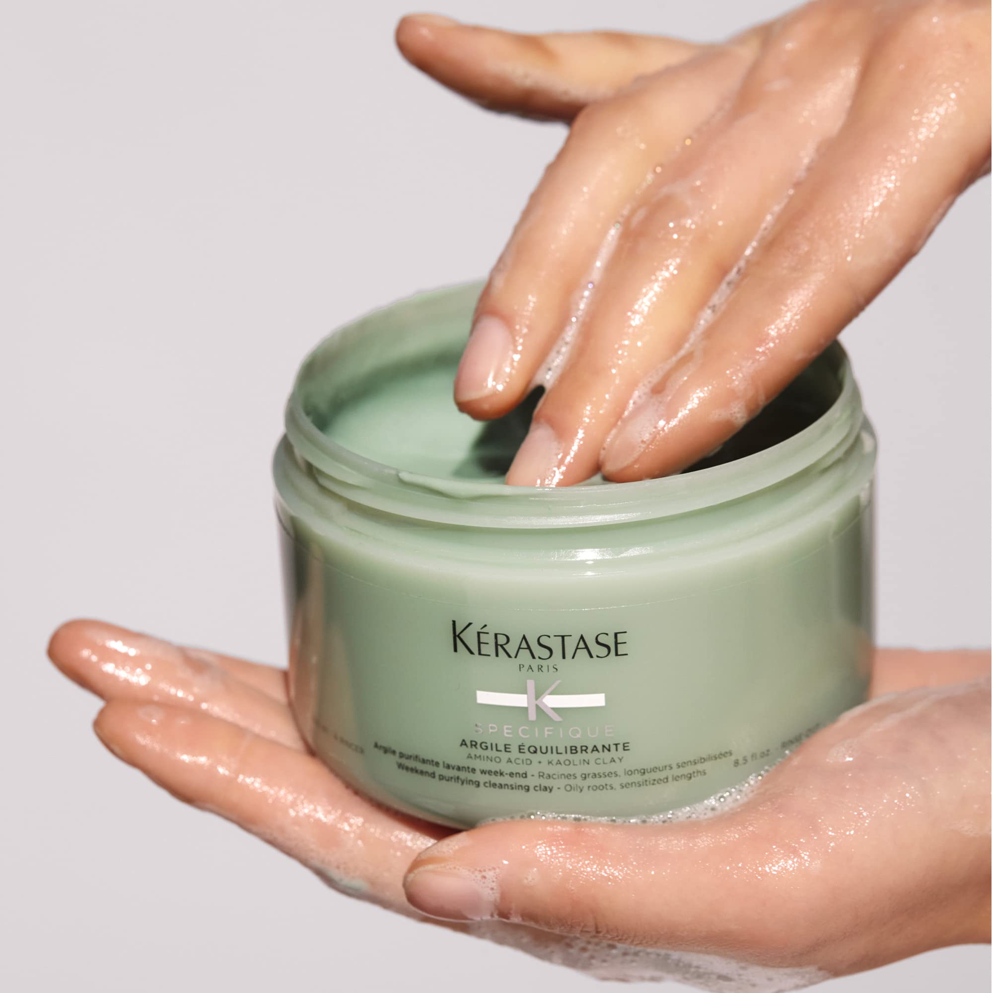 Kerastase clay shampoo UAE in a green jar with hands applying the product for balanced hair care