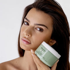 Kerastase clay shampoo UAE in a green jar held by a woman, perfect for revitalizing hair care