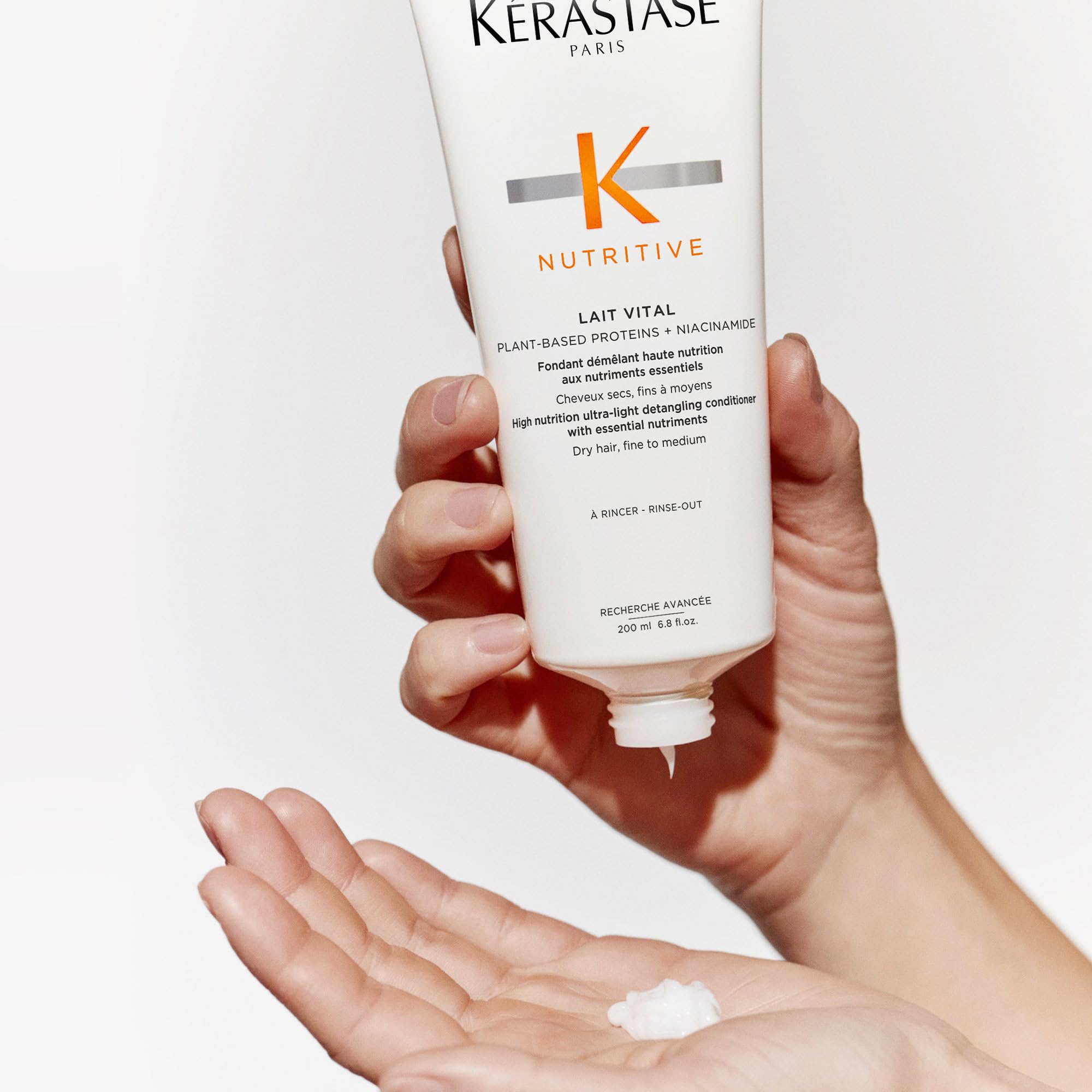 Kérastase Nutritive Lait Vital conditioner in a palm with smooth creamy texture for dry hair nourishment