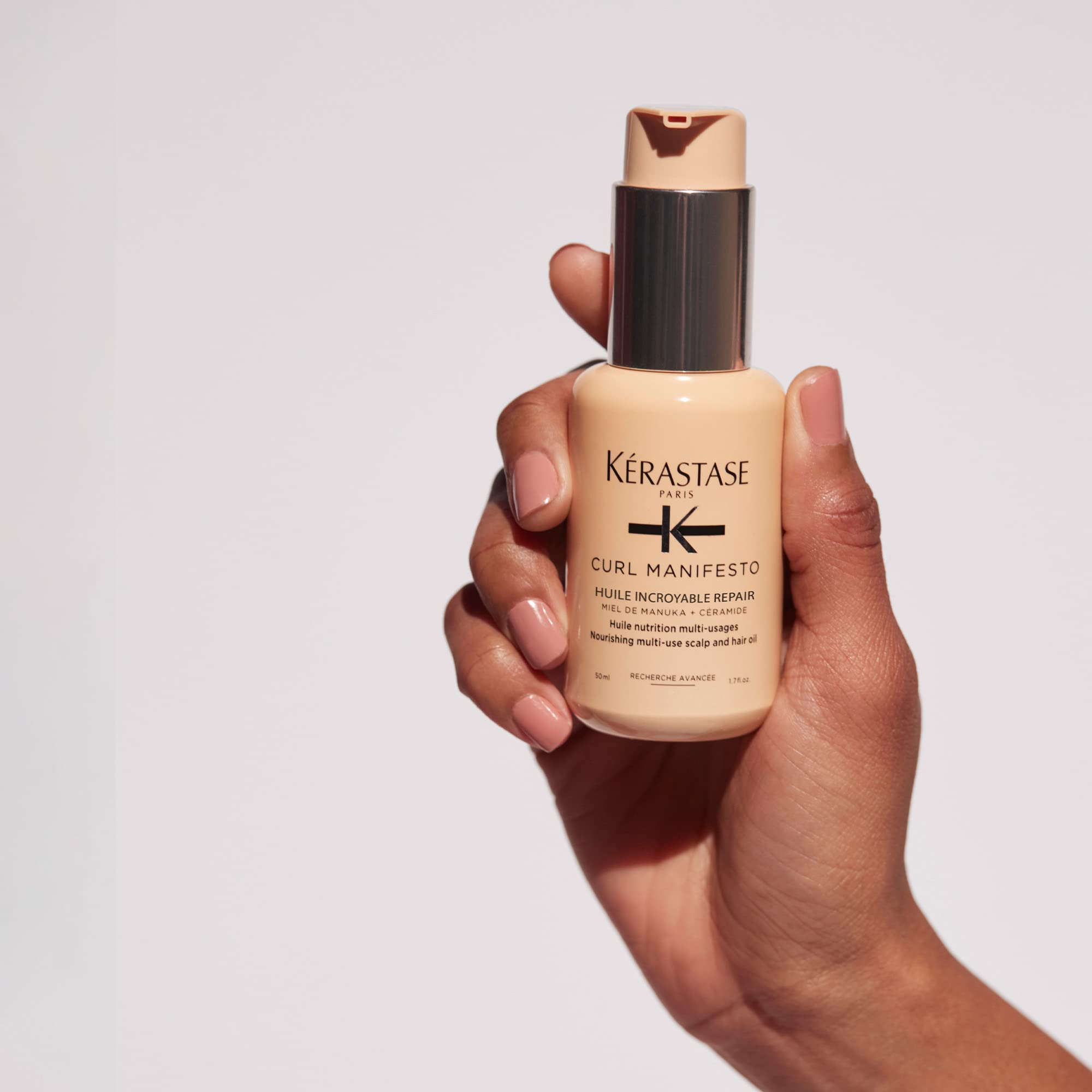 Kerastase Sublime Repair Oil for hair in a hand with a sleek bottle design