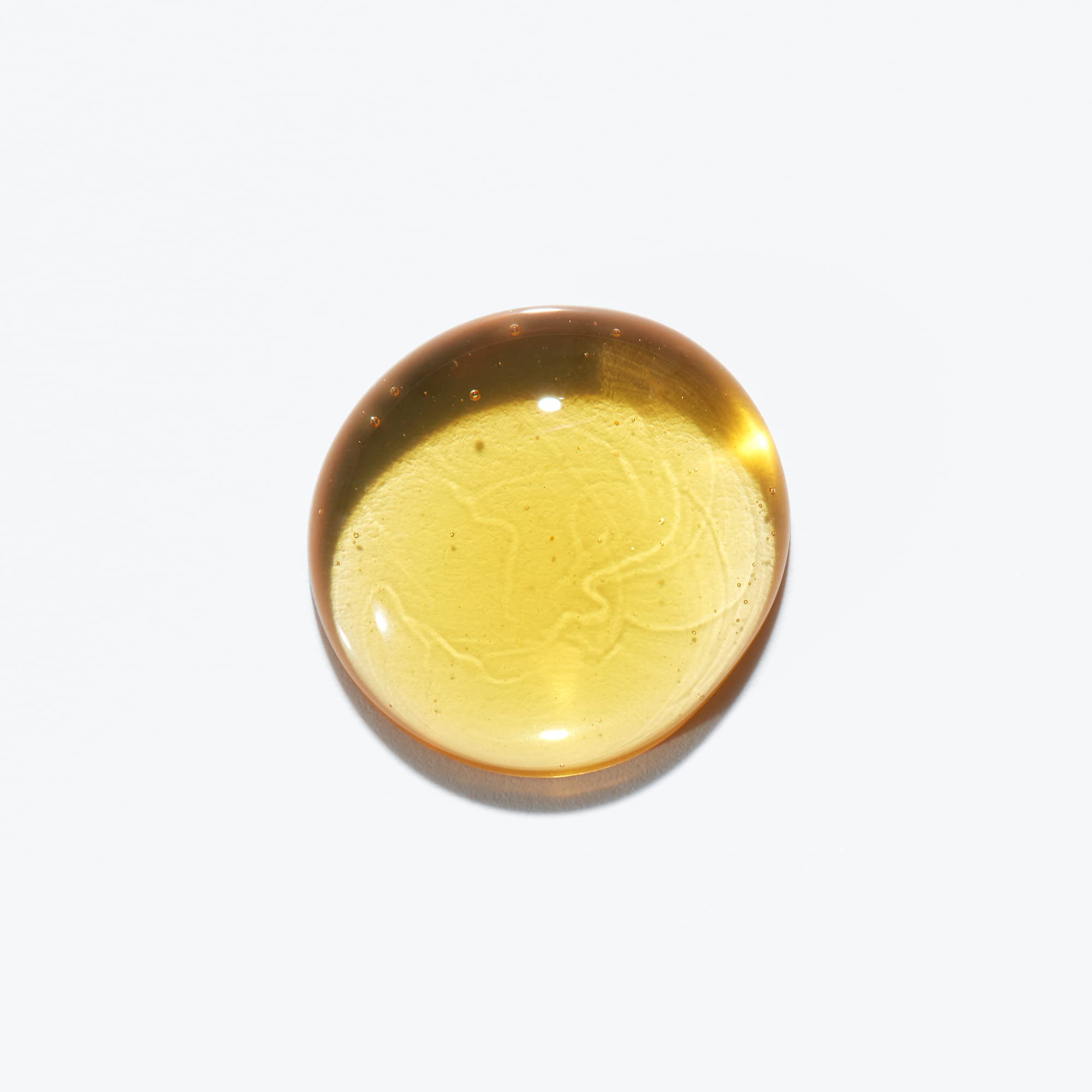 Kerastase Sublime Repair Oil for hair in a circular drop showcasing its rich golden color and smooth texture