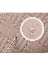 Quilted light beige baby travel bag with circular logo patch detail