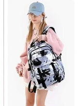 Black and white splatter kids backpack on shoulder, front pocket and adjustable straps