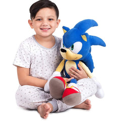 Young boy holding a kids sonic plush pillow toy wearing pajamas and smiling