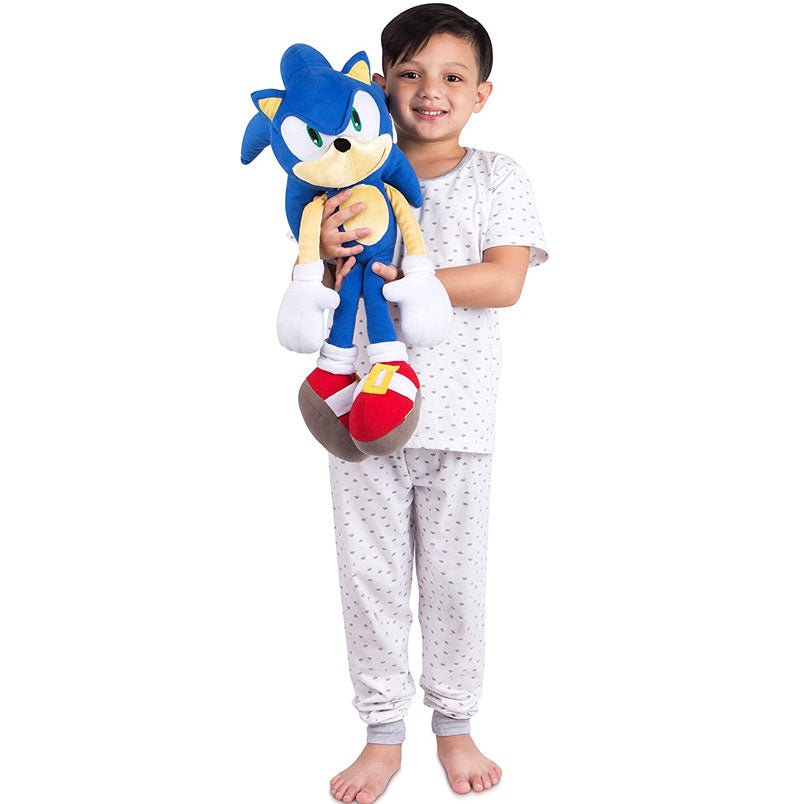 Child holding a blue kids sonic plush pillow toy wearing white pajamas with small patterns