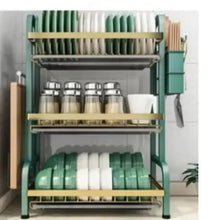 3-tier dish rack with green and white bowls on lower shelf and cups on middle tier