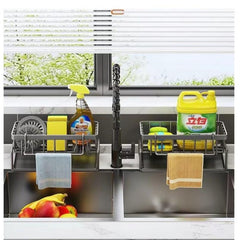 Huitich stainless steel sink organizer with dual compartments holding cleaning supplies and towels over a double kitchen sink