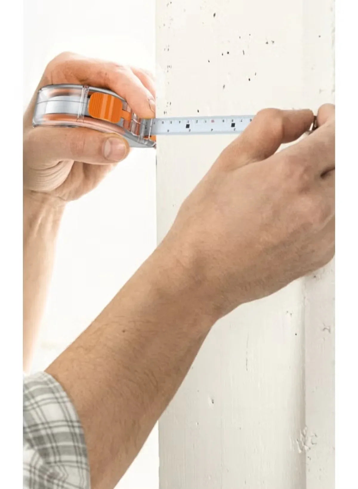 Hands measuring a wall edge with a tape measure