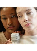 Two people holding a small white facial moisturizer jar between them