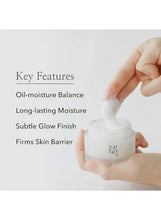 White facial moisturizer jar held open in hands with jar and lid visible