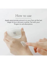 Hands holding a small white moisturizer jar while applying product
