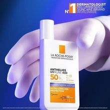 Anthelios UVmune 400 SPF 50+ anti-dark spots fluid bottle held in glove.