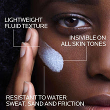Anti-dark spots sunscreen fluid applied as a pale cream on fingertips.