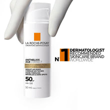 Sunscreen bottle with white cap held in gloved hands, orange label