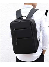 Black backpack worn by person, front zip pocket and adjustable shoulder straps