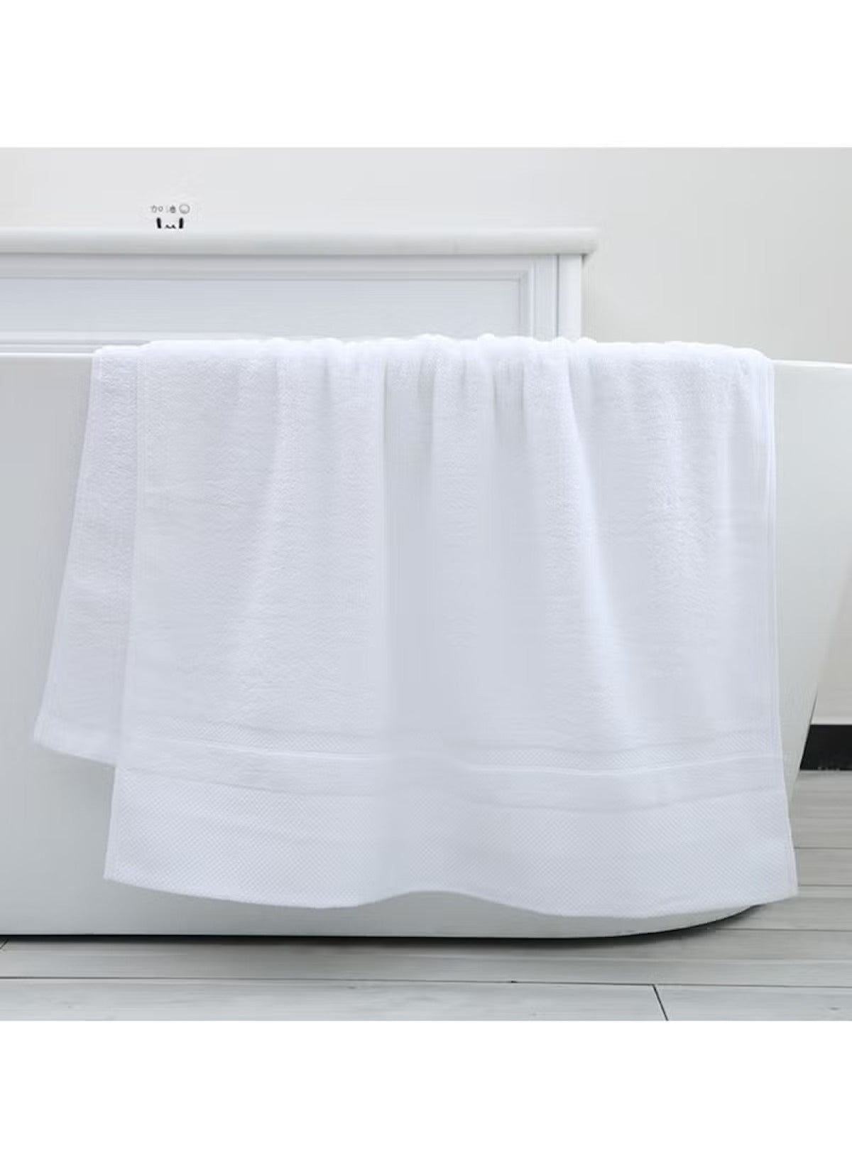 Large White Bath towel 70x140 cm 470g hanging on a white bathtub in a modern bathroom