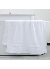 Large White Bath towel 70x140 cm 470g hanging on a white bathtub in a modern bathroom