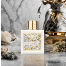 Gold-capped perfume bottle with ornate cream-and-gold label on reflective surface