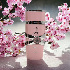 Lattafa Yara perfume for women in a pink bottle with silver accents surrounded by pink cherry blossoms