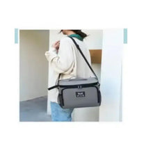 Grey leak-proof lunch box crossbody with adjustable strap worn over shoulder