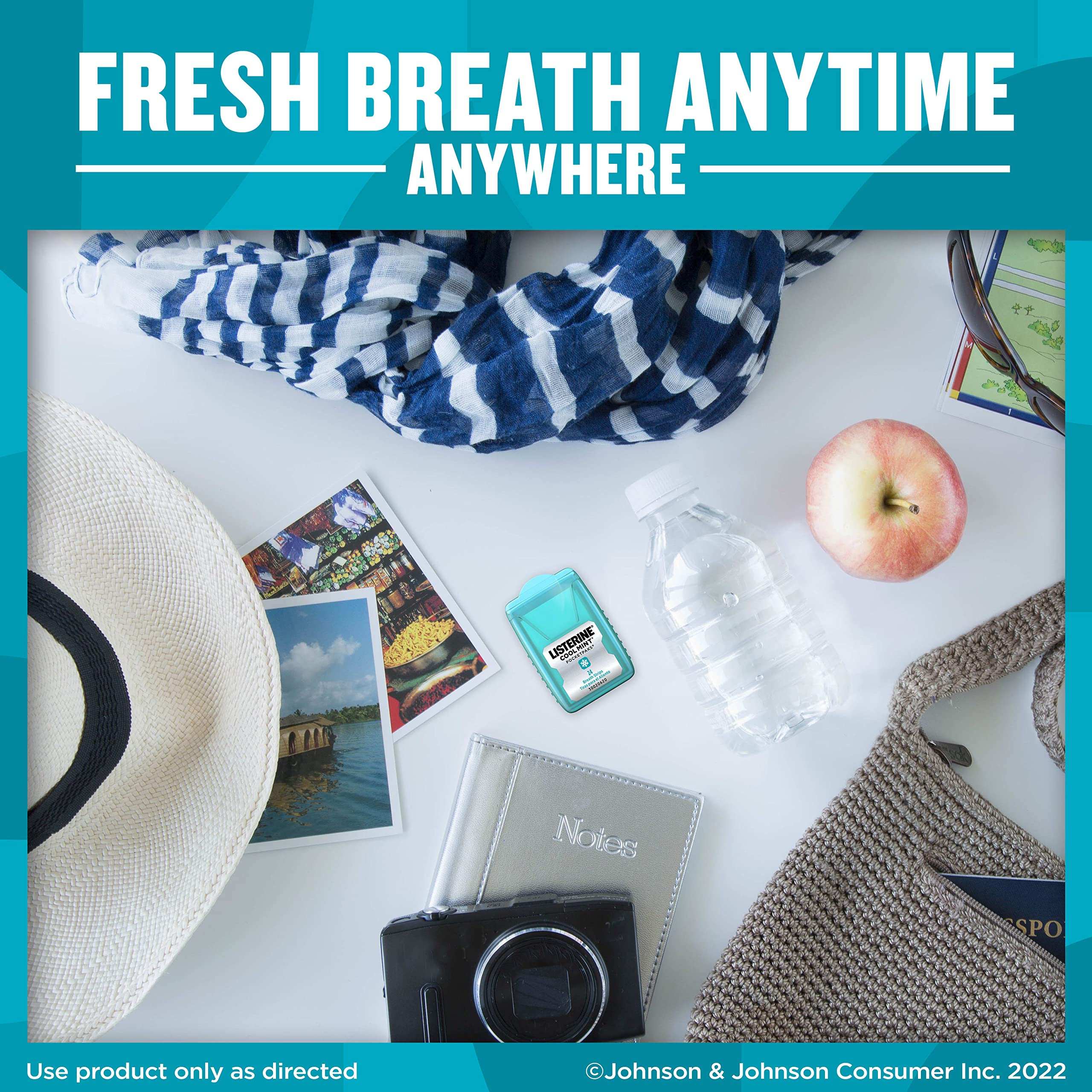 Travel flat lay with hat camera water bottle apple bag and pack of Listerine Cool Mint Breath Strips