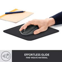Black mouse pad with hand using mouse on desk surface, logi logo