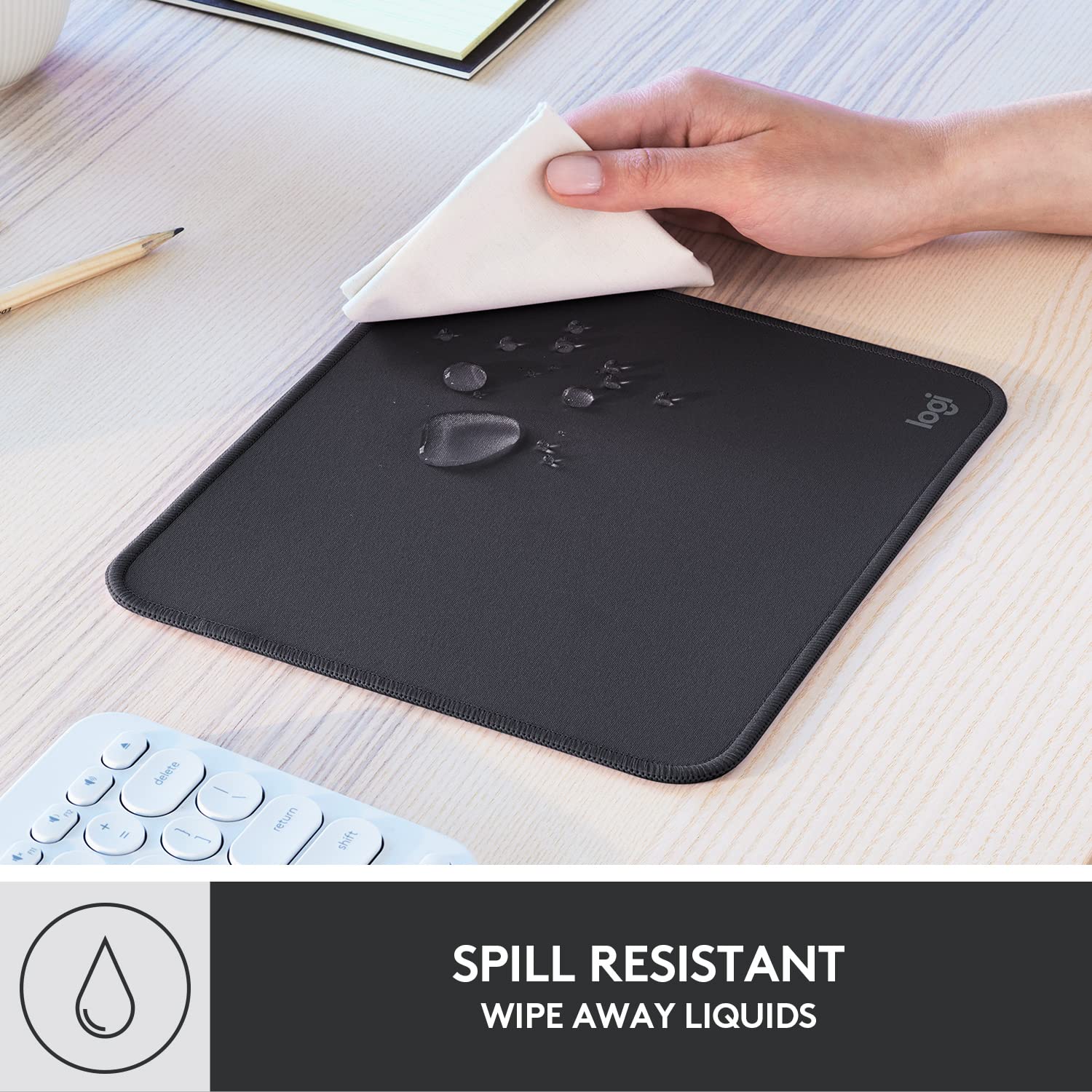 Logitech black anti-slip computer mouse mat with spill resistant surface being wiped clean