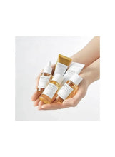 Hand holding Centella travel skincare bottles and tubes in yellow and white