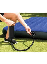 Inflation pump with hose connected to an outdoor inflatable, shown during use