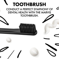 Marvis medium toothbrush black handle and bristles with white toothpaste swirls on white background